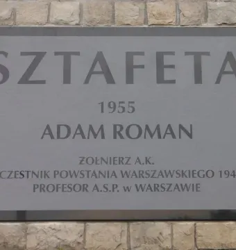 Plaque for Sztafeta with the year 1955, Adam Roman’s name, and Polish biographical text.