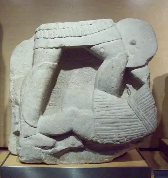 Stone relief fragment of the Acrobat from Osuna showing a contorted human figure with bent limbs and a tilted head.