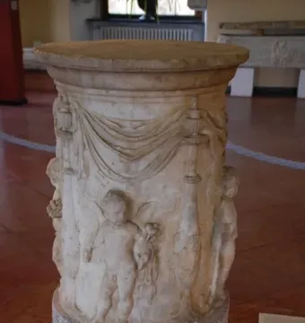 Four Seasons Altar with carved putti and draped decoration on a round marble pedestal.
