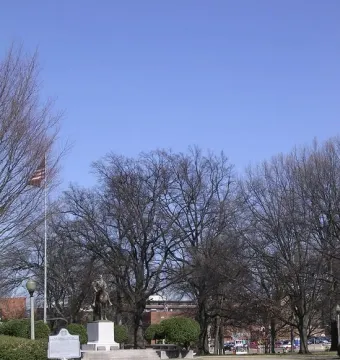Nathan Bedford Forrest Monument, an equestrian statue on a pedestal in a park with bare trees and a historical marker nearby.