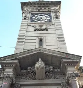 Brighton Clock Tower with an ornate stone facade, clock face, ship figurehead, and Queen Victoria mosaic portrait