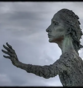 La madre del emigrante bronze statue of a woman in profile with an outstretched hand