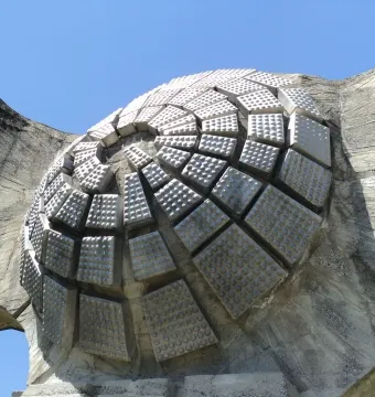 Textured dome detail of the Monument to the Revolution of the People of Moslavina against a blue sky.