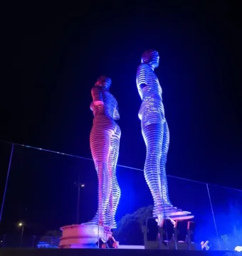 Ali and Nino sculpture illuminated in blue and magenta at night