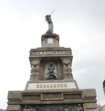 Cuauhtémoc Monument with tiered stone reliefs and a statue holding a spear-like object on top