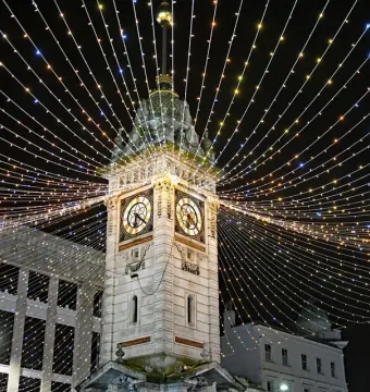 Jubilee Clock Tower at night with strands of Christmas lights radiating from the top against a dark sky.