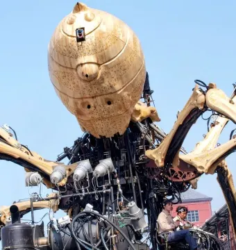 La Princesse giant mechanical spider with a rounded body and long articulated legs against a blue sky.