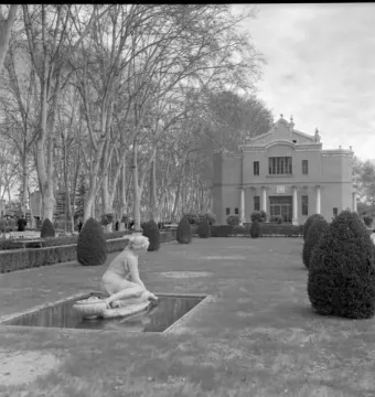 Mermaid Fountain with a pale kneeling female statue touching the water in a rectangular basin.