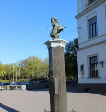 Pushkin bust on a tall column behind a decorative iron fence