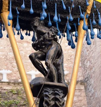 Rainy Taxi sculpture with two grappling figures beneath hanging blue teardrops
