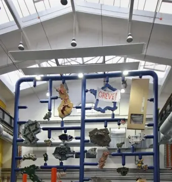 Entropa sculpture with a blue framework suspending irregular shapes in a spacious room.