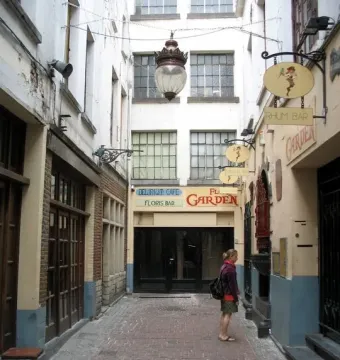 Jeanneke Pis barely visible in a dark alcove on the right wall of the alley.
