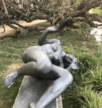 The River, a dark reclining nude female sculpture on a stone plinth outdoors.