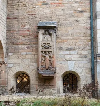 Tomb of Bruno the Priest carved in relief on a tall stone monument set into a church wall.