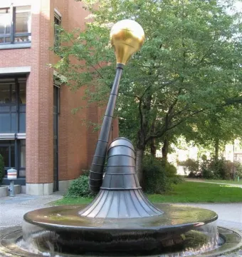 Erich-Schulze-Brunnen fountain with a dark metal sculpture rising from a circular stone basin.