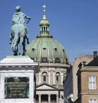 Frederick V equestrian statue seen from behind on a marble pedestal, with a domed church and classical buildings in the background.