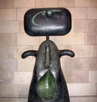 Femme by Joan Miró, a dark abstract sculpture with a rounded head, curved arm-like forms, and a green teardrop shape on the front.