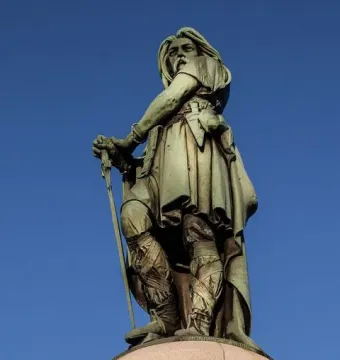 Vercingetorix Monument, a bronze warrior statue holding a sword against a blue sky