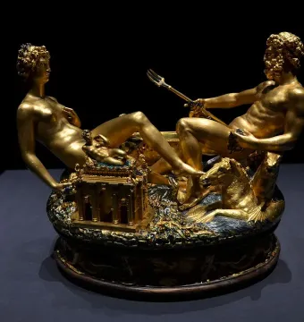 Cellini Salt Cellar with a reclining female figure and a seated male figure holding a trident on a detailed golden base.