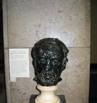Bronze bust of Man with the Broken Nose showing a wrinkled face and flattened nose on a marble pedestal.