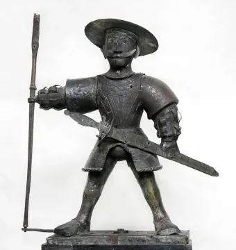 Old Thomas weather vane figure in armor with a wide-brimmed hat, mustache, staff, and sword.