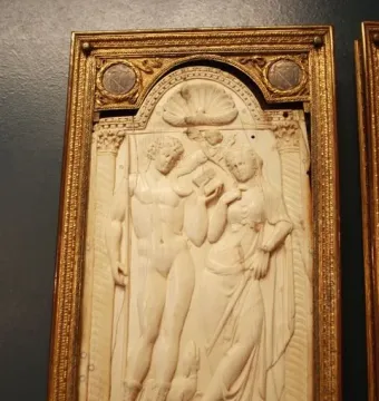 Queriniano Diptych ivory relief panel with a male and draped female figure under an arch, flanked by columns and a small winged figure.