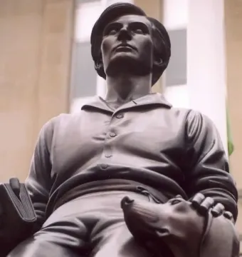 Abraham Lincoln: The Hoosier Youth bronze sculpture of a seated young man holding a book, with a dog resting beside him.