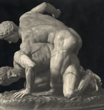 Classical marble sculpture of two wrestlers locked in a struggle, one atop the other against a dark background.