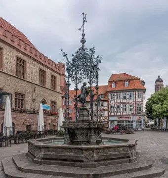 Gänseliesel Fountain with a bronze girl sculpture under an ornate canopy in Göttingen\'s town square.