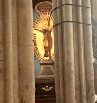 Gero Cross crucifix with Christ before a golden sunburst, framed by stone columns.