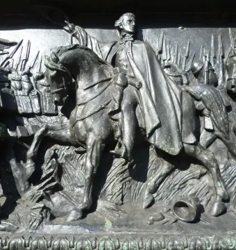 Bronze relief panel on the Duke of Wellington statue showing a mounted figure and soldiers in a battle scene.