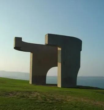 Elogio del Horizonte concrete sculpture on a grassy hill overlooking the sea
