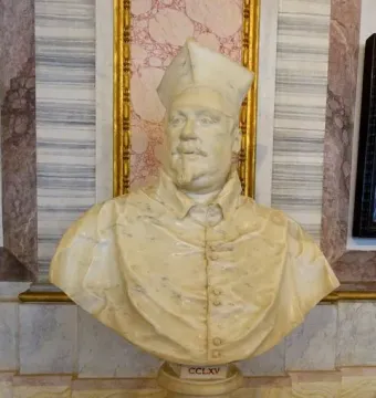 Bust of Cardinal Scipione Borghese in cream-colored marble, shown wearing a cap and buttoned garment with a mustache and goatee.