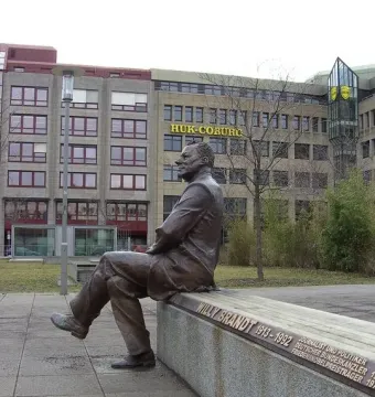 Willy Brandt Memorial bronze statue of a seated man on a long bench outdoors.