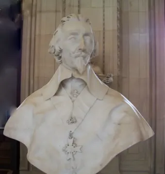 Bust of Cardinal Richelieu in white marble, showing curly hair, a mustache, a pointed beard, and a draped cape with a hanging cross medallion.