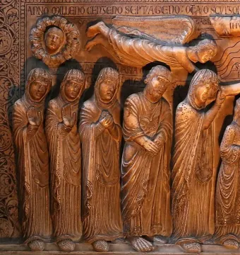 Marble relief from Descent from the Cross showing sorrowful robed figures beneath an inscription band, with a winged figure and a round medallion above.