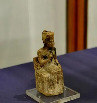 Khufu statuette showing a seated figure wearing a tall rectangular headdress on a clear base.