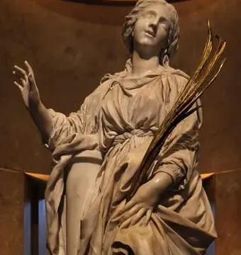 St Bibiana marble sculpture gazing upward, with one hand raised and the other holding golden fronds.