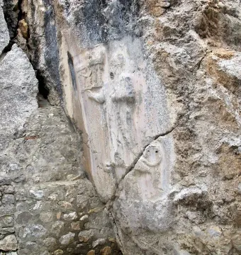 Bas-relief carvings on the rock face at Yazılıkaya, with stylized figures carved into a smoother section of stone.