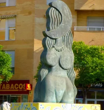 Dona Lluna bronze sculpture of a stylized female figure with a crescent moon above her head on a yellow patterned pedestal.