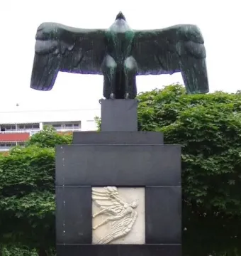 Flygarmonumentet showing a dark bird sculpture with outstretched wings atop a tiered stone pedestal.