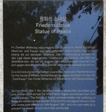 Informational plaque for the Statue of Peace with Korean, German, and English text on a stone base.