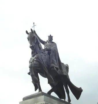 The Apotheosis of St. Louis, a bronze equestrian statue of a crowned figure holding a sword aloft, seen from below against an overcast sky.