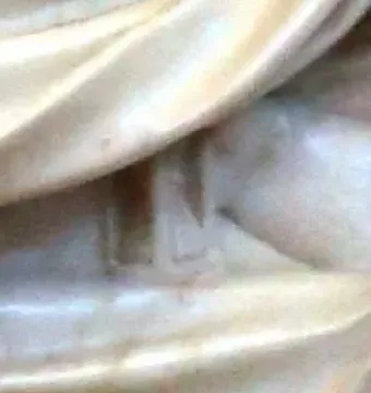 Close-up of light marble drapery with faint carved lettering on the Tomb of Ferdinand van den Eynde.