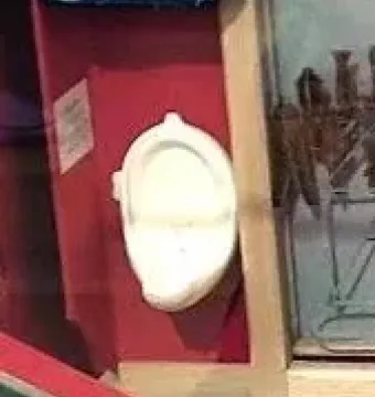 Marcel Duchamp’s Fountain, a white porcelain urinal mounted vertically against a red background.