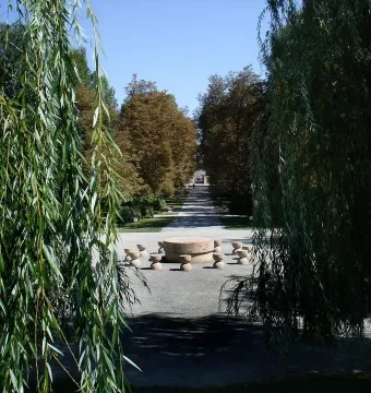 The Table of Silence with its circular stone table and surrounding seats along a tree-lined gravel path.