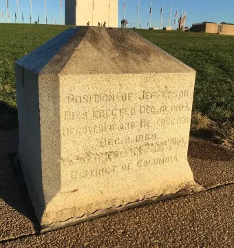 Jefferson Pier stone monument with carved lettering on a paved area near grass.
