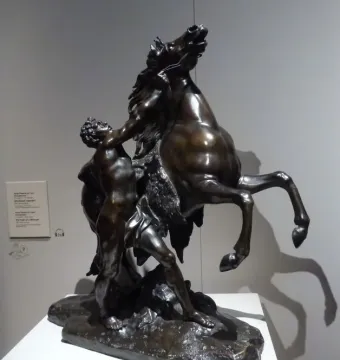 Marly Horses, a dark bronze sculpture of a muscular man restraining a rearing horse.