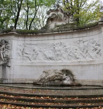 Monument to the Belgian Pioneers in Congo with a curved stone frieze and sculpted figures above a shallow pool