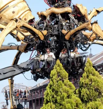 La Princesse mechanical spider with four operators seated inside its central body against a blue sky.